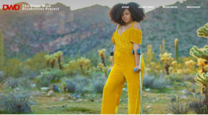 black woman in yellow jumpsuit with arm crutches in desert. on back ground words DWD the Divas With Disabilities Project