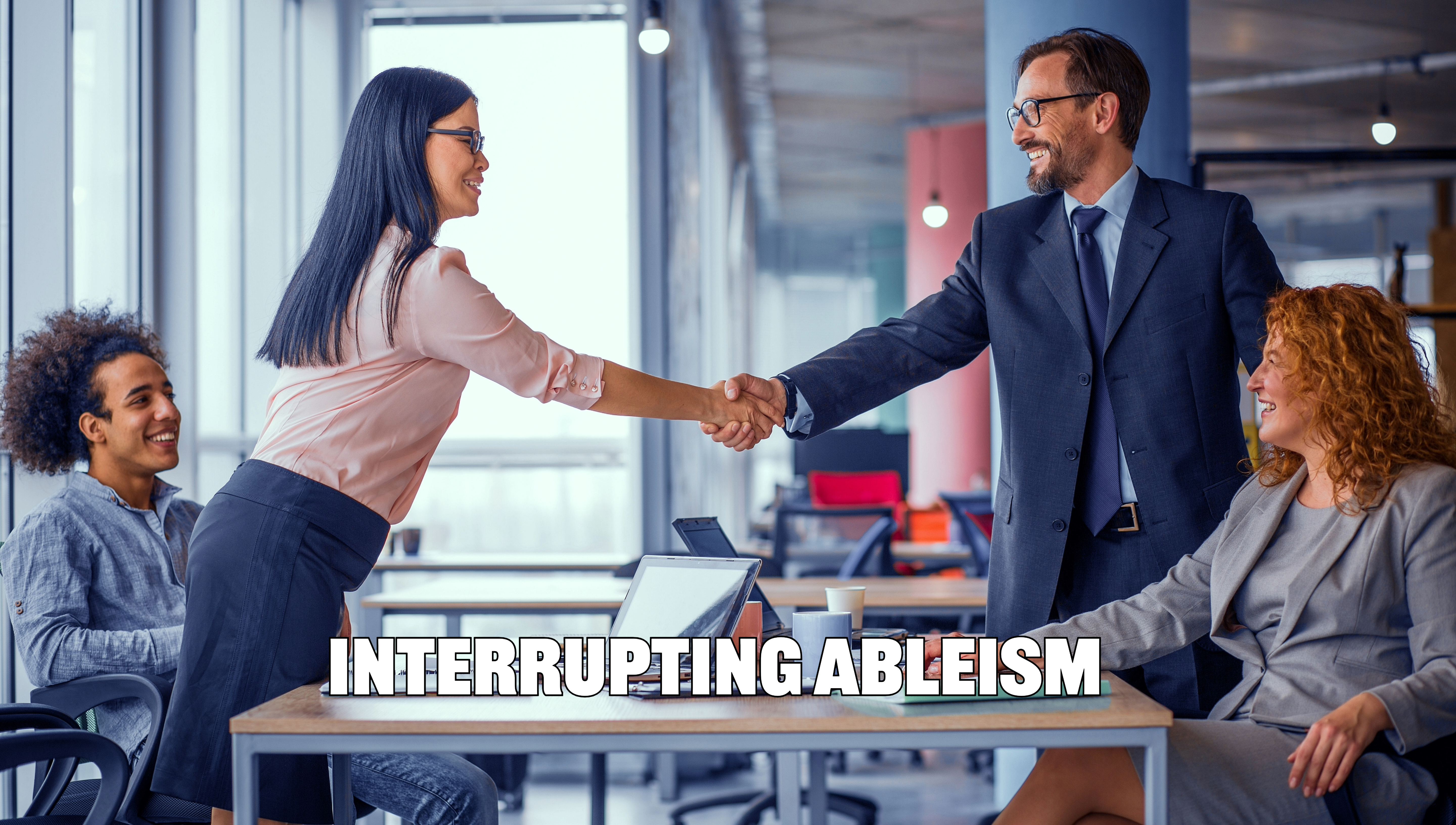 a group of diverse people surround a table. two shake hands.